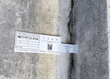 G1-Riss-Messlehre - Rissmonitor für innen und außen - mit QR-Code in einer Ecke über dem Riss montiert.