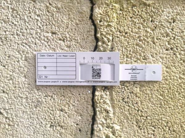 G1-Riss-Messlehre - Rissmonitor für innen und außen - mit QR-Code waagerecht über einem Riss montiert.