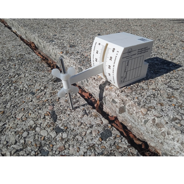 G3-Riss-Messlehre in frontaler Ansicht mit Skala zur Ablesung der Versatzhöhe sowie der Versatztaster, der auf einem tieferliegenden Natursteinbelag aufsitzt.